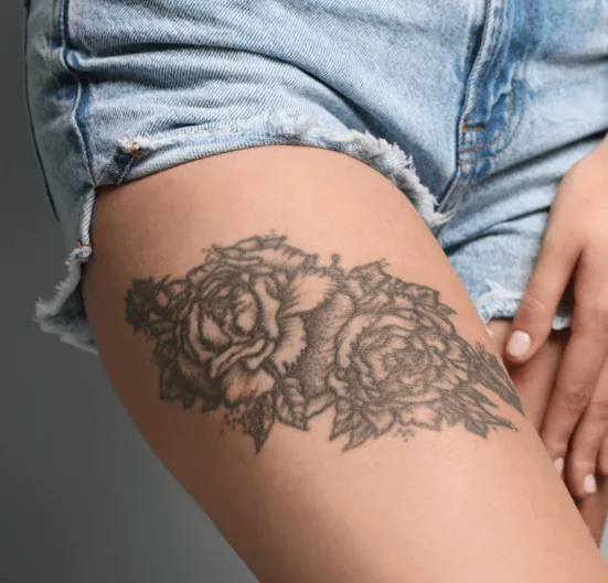 Large black-and-grey floral tattoo covering the upper thigh